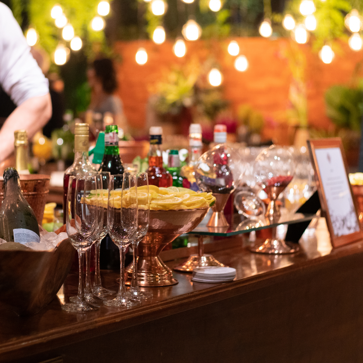 signature-drink-bar Outdoor bar with champagne on ice, elegant glassware, and garnishes under warm ambient lighting.